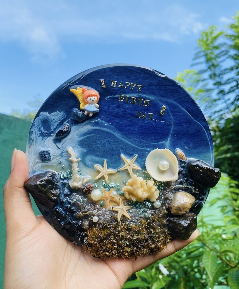 A round beach-themed resin birthday plaque with a fairy figurine and starfish