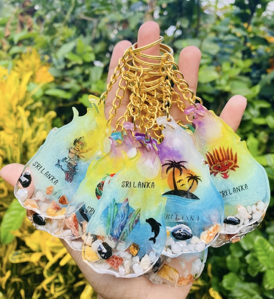 A hand holding colourful Sri Lanka souvenir resin keychains